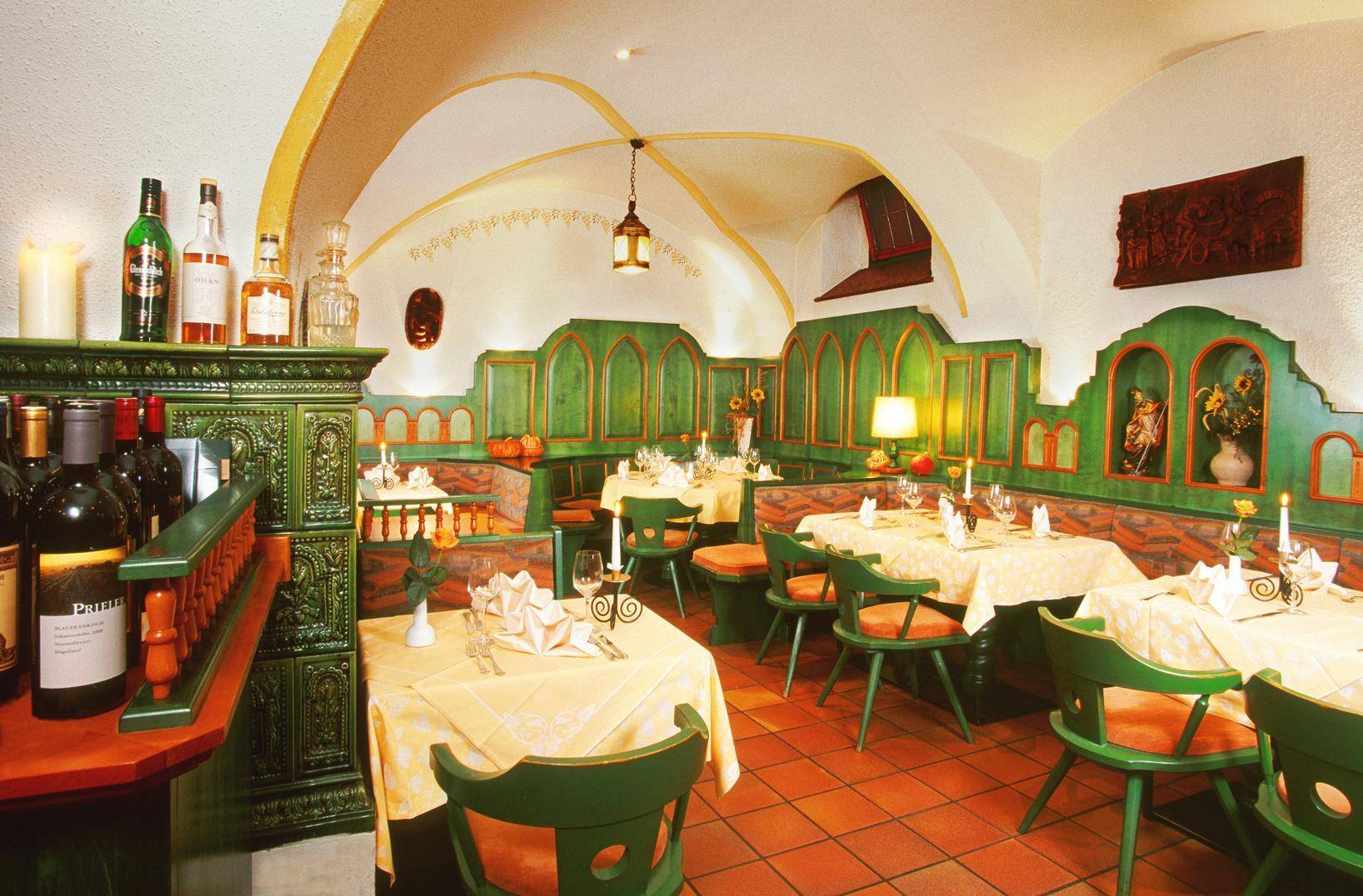 Traditioneller Restaurantbereich mit Gewölbedecke, Terrakottafliesen und grünen Holzelementen, gemütlich beleuchtet.