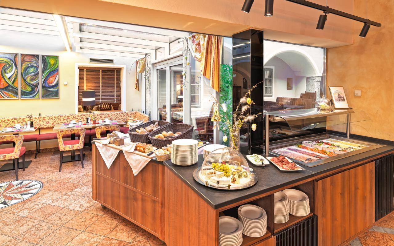 Buffetbereich mit einer Auswahl an Speisen, umgeben von einem hellen Restaurantbereich mit Kunstwerken.