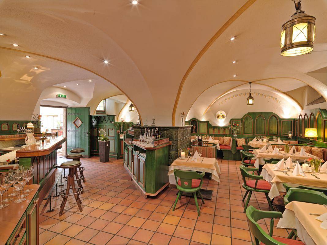 Traditioneller Restaurantbereich mit Gewölbedecke, Terrakottafliesen und grünen Holzelementen, gemütlich beleuchtet.