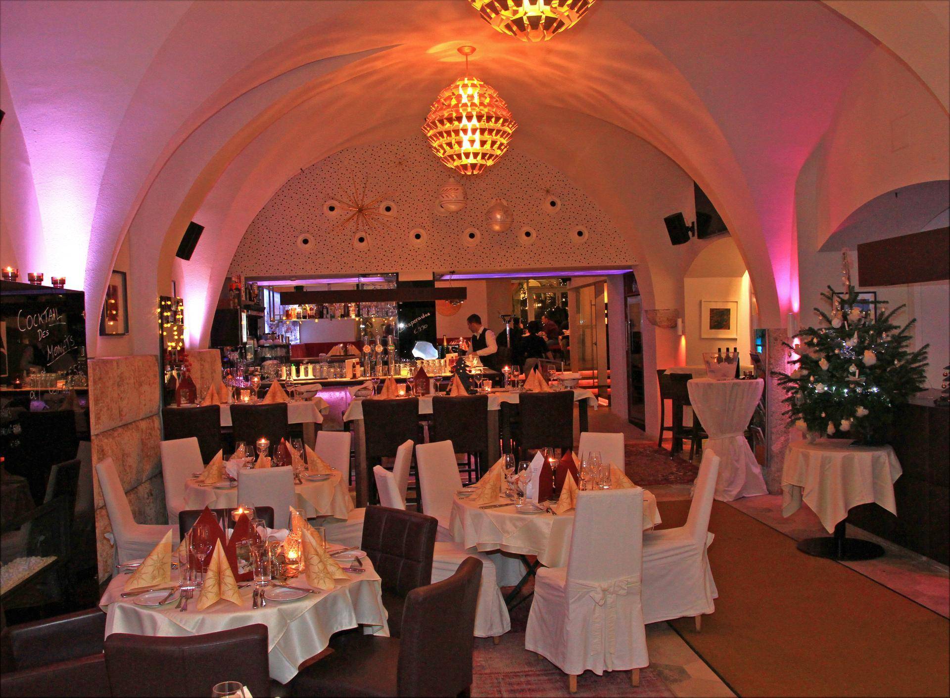 Festlich gedeckter Restaurantbereich in einem Gewölbekeller mit stimmungsvoller Beleuchtung und Weihnachtsdekoration.