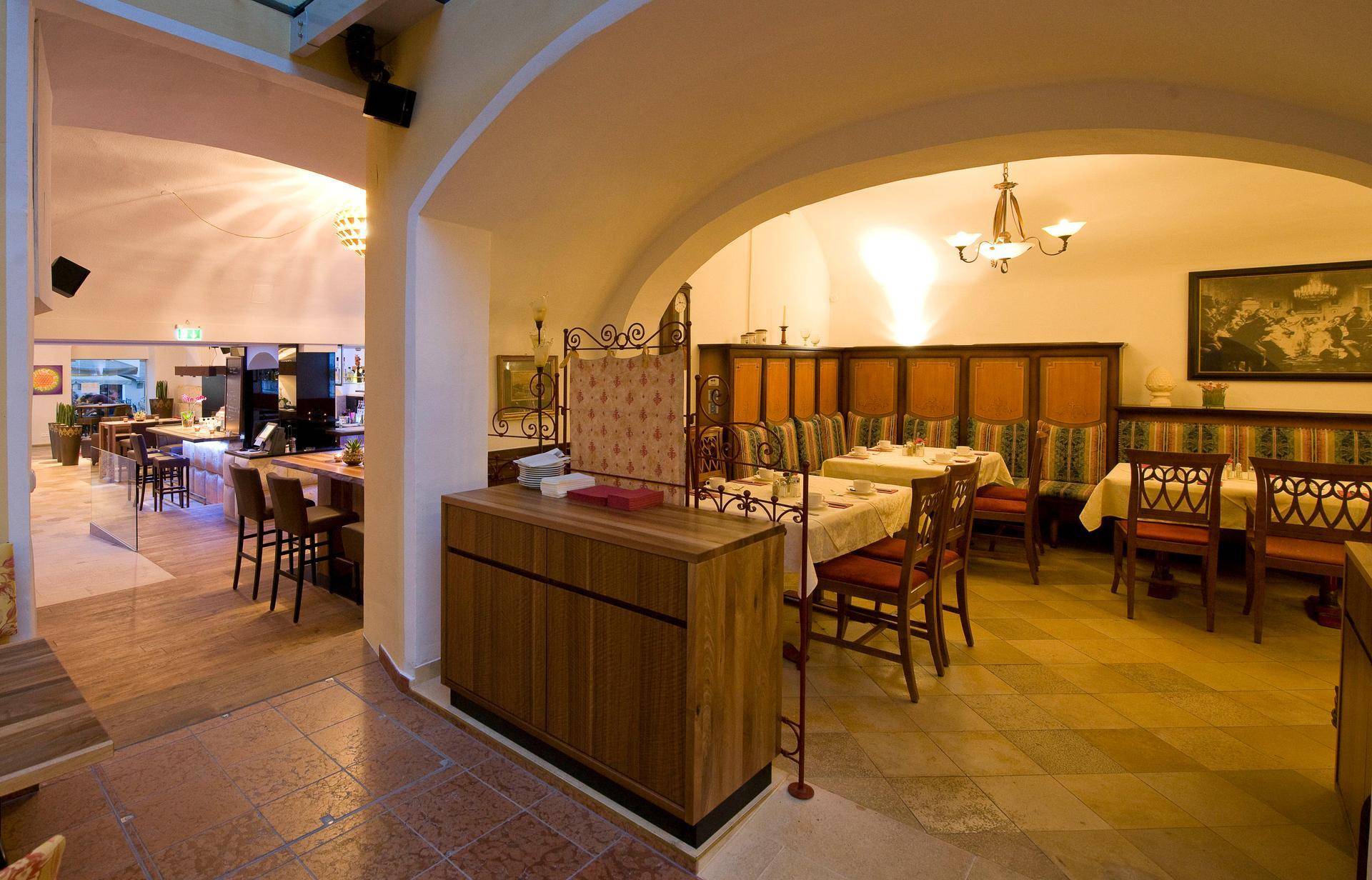 Restaurantbereich mit Gewölbedecke, Holzelementen und Übergang zu einem modernen Barbereich.