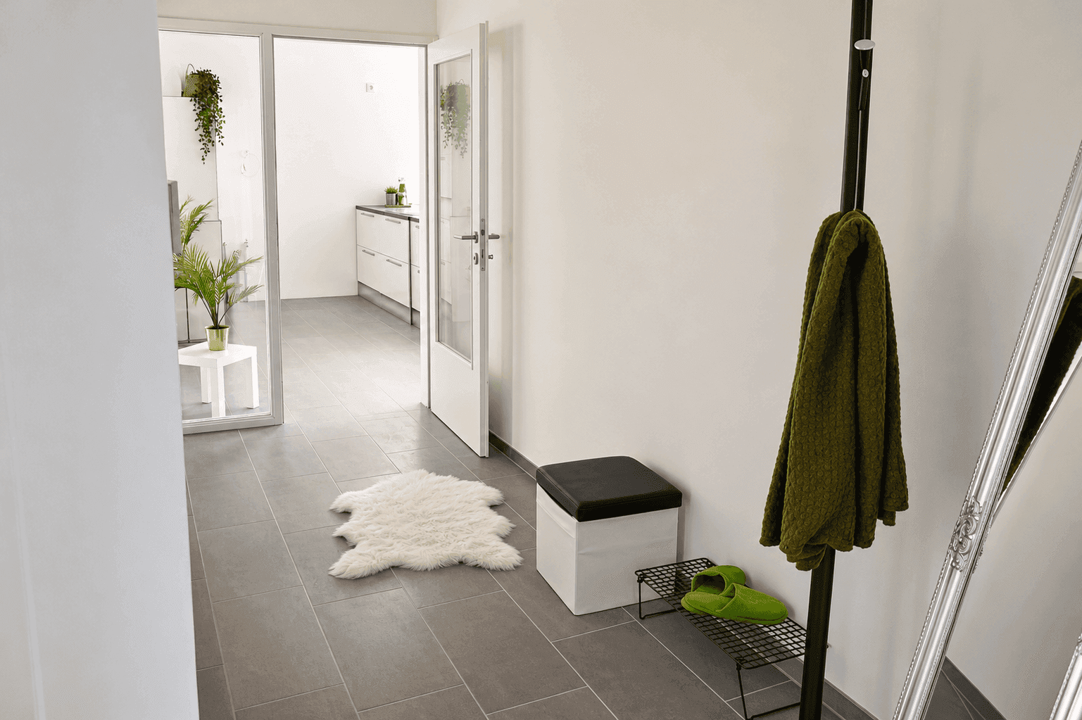 Heller Flur mit Fliesenboden, Garderobe und Blick in die Küche.