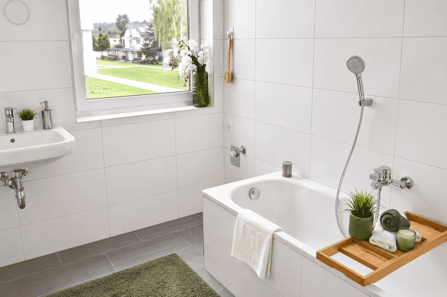 Modernes Badezimmer mit Badewanne, weißen Fliesen und Fenster mit Grünblick.