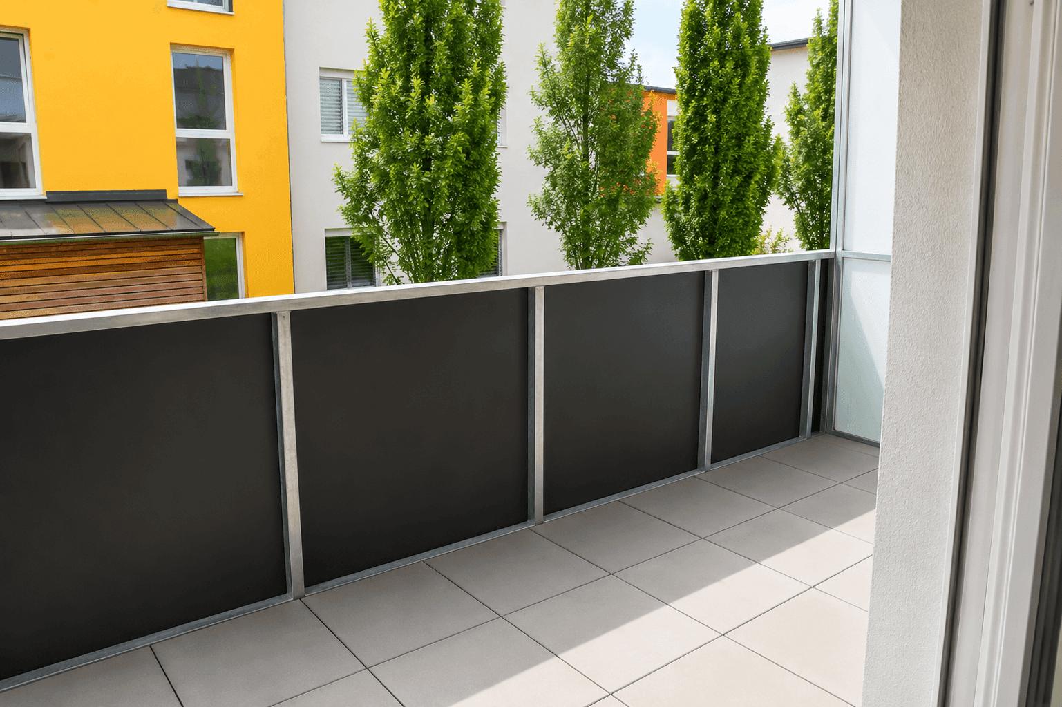 Moderner Balkon mit Fliesenboden und Blick auf die umliegenden Gebäude und grüne Bäume.