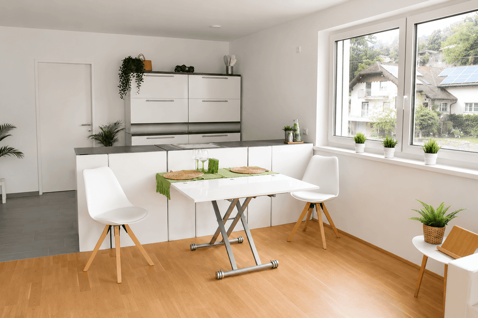 Moderne Küche mit weißen Schränken, Essbereich und großem Fenster mit Ausblick.