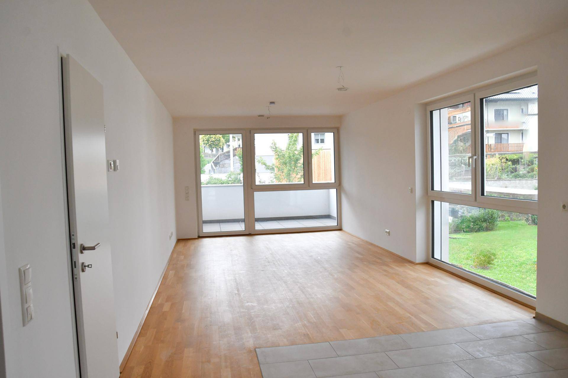 Geräumiges, helles Wohnzimmer mit Holzboden und Zugang zu einem Balkon, ideal für offenes Wohnen.