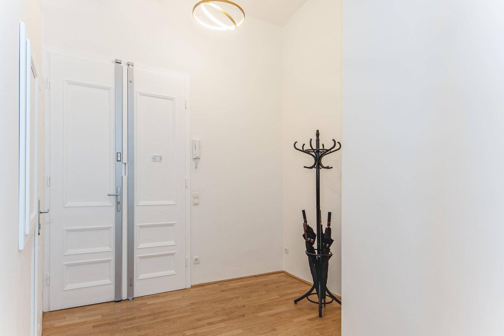 Eingangsbereich mit Parkettboden, Garderobe und einer Doppeltür.