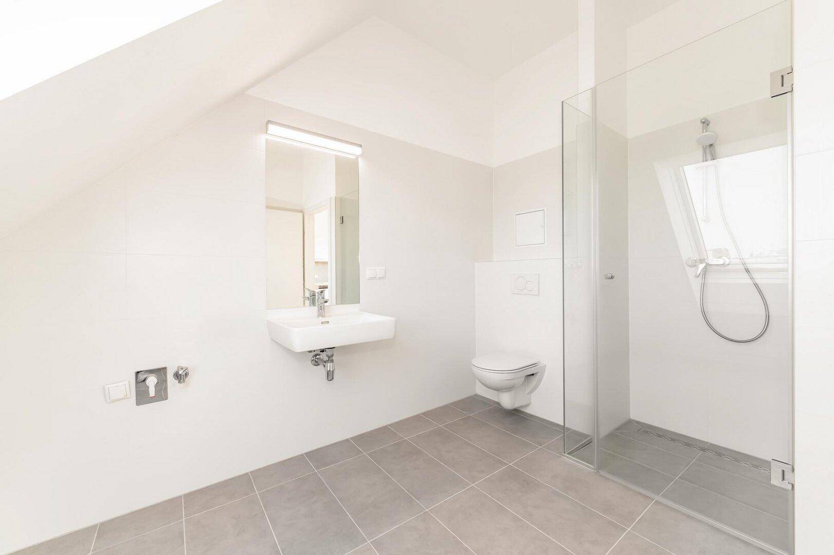 Helles modernes Badezimmer mit ebenerdiger Dusche, wandhängendem WC, Einzelwaschbecken und Dachfenster.