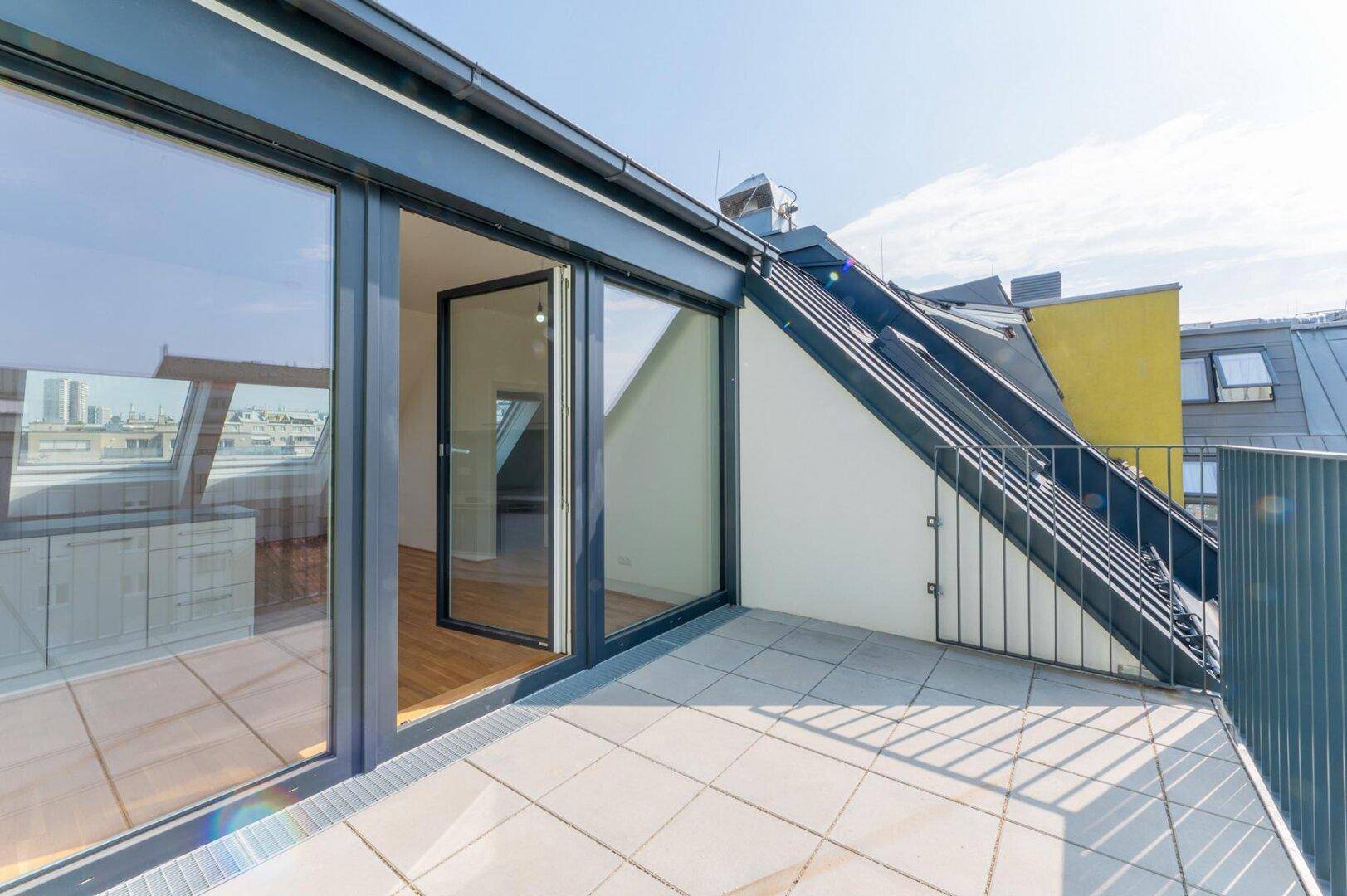 Geräumiger Balkon mit Fliesenboden und großen Glasschiebetüren, die den Zugang zum Innenbereich ermöglichen.