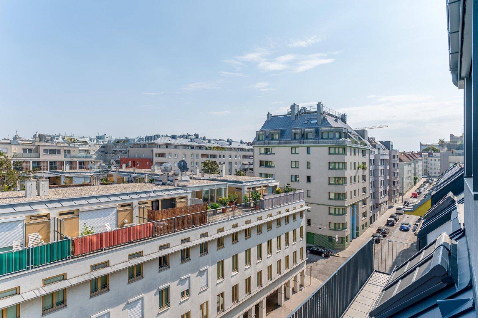 Weitläufiger Blick über eine belebte Stadtstraße mit modernen und traditionellen Gebäuden unter blauem Himmel.