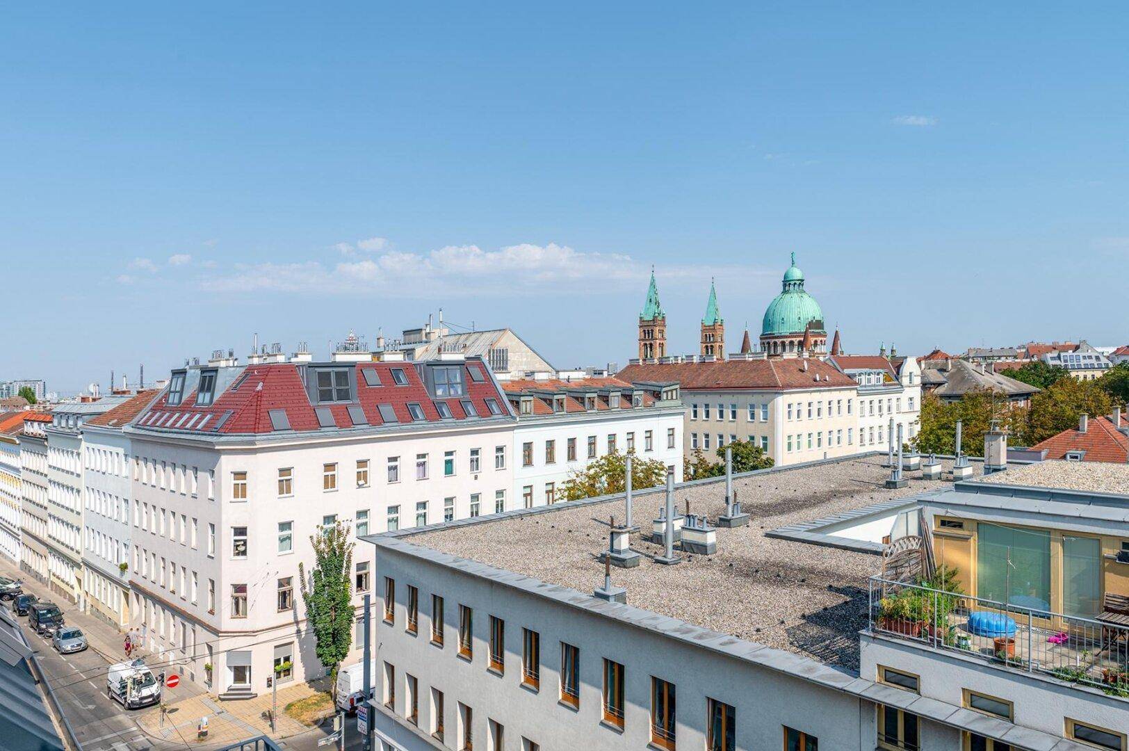Panoramablick über die Stadt mit historischen Gebäuden, Dächern und einer markanten Kirche im Hintergrund.