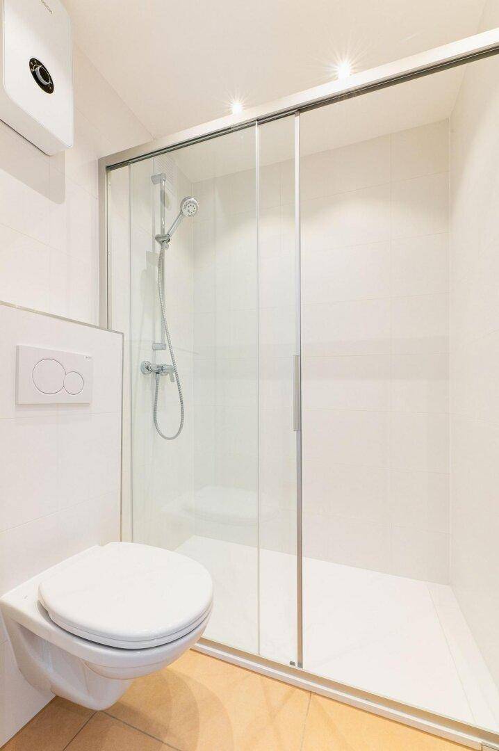 Modernes Badezimmer mit wandhängendem WC und geräumiger Duschkabine.
