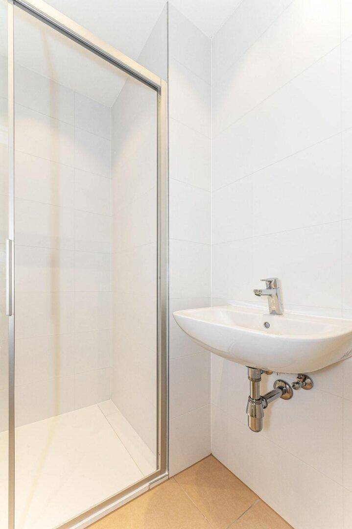 Helles Badezimmer mit Duschkabine und modernem Waschbecken.