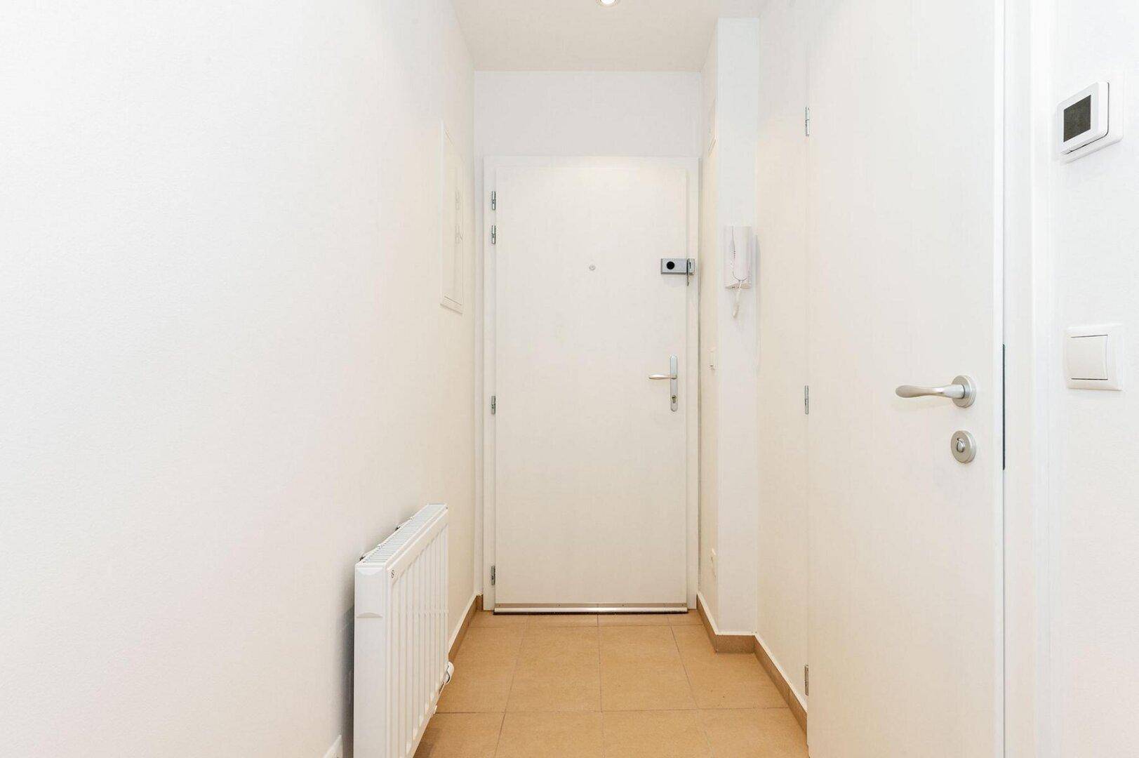 Eingangsbereich mit Fliesenboden und weißer Wohnungstür.