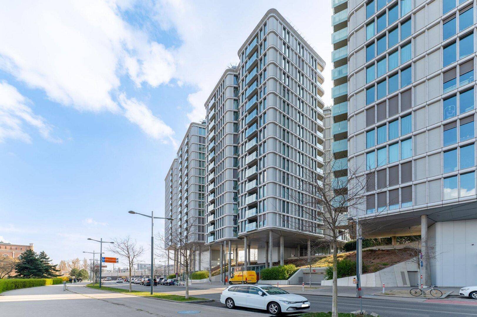 Zeitgenössische Wohngebäude mit markanter Architektur und vielen Balkonen entlang einer Straße.