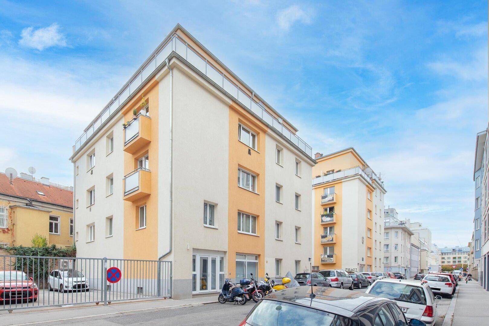 Modernes Wohngebäude mit Balkonen und einer hellen Fassade an einer städtischen Straße.