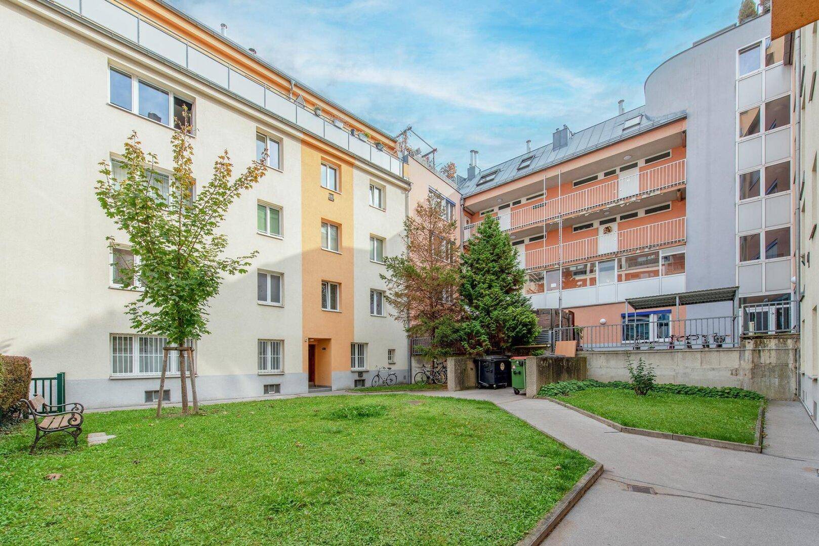 Innenhof mit Rasenfläche, Bäumen und Blick auf die umliegenden Wohngebäude.