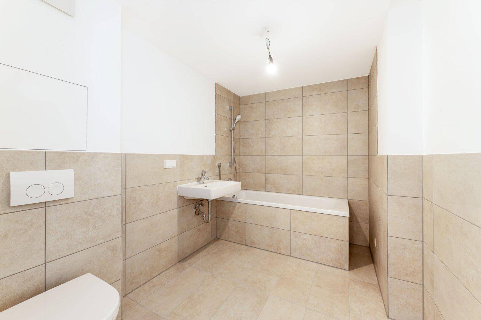 Modernes Badezimmer mit beigefarbenen Fliesen, Badewanne und wandhängendem WC.