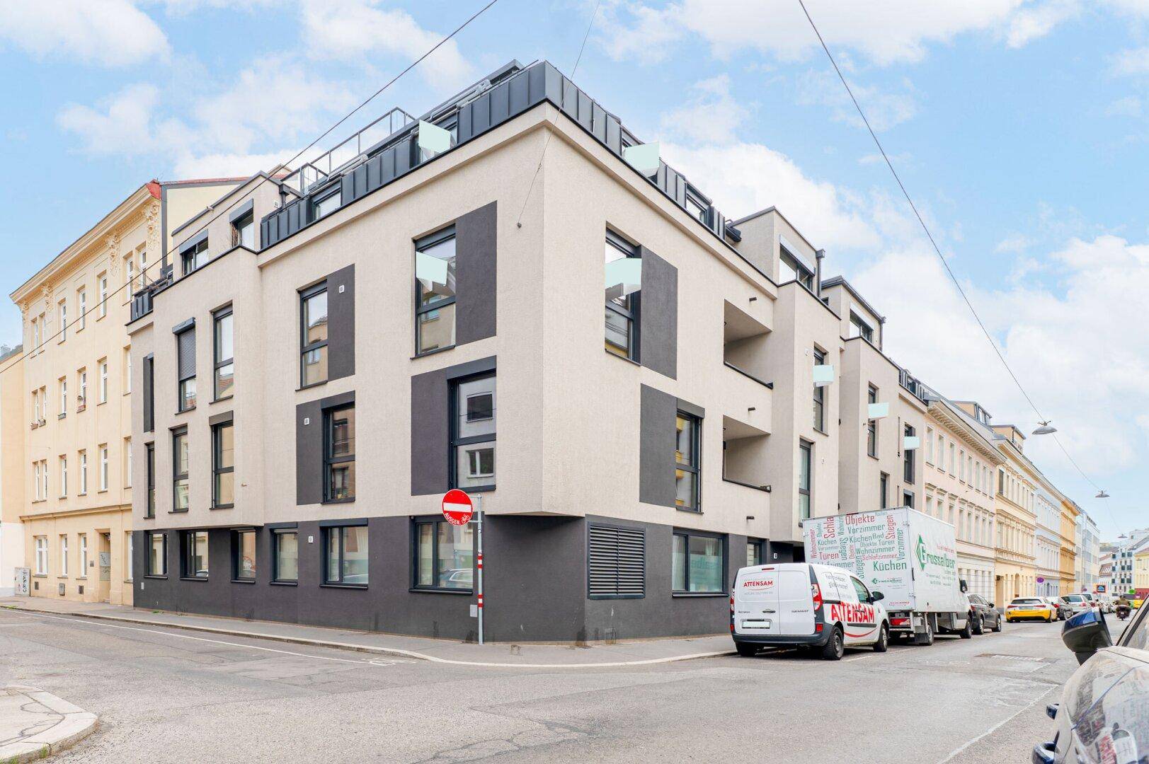 Eckansicht eines modernen Wohngebäudes mit klarer Linienführung und großen Fensterflächen.