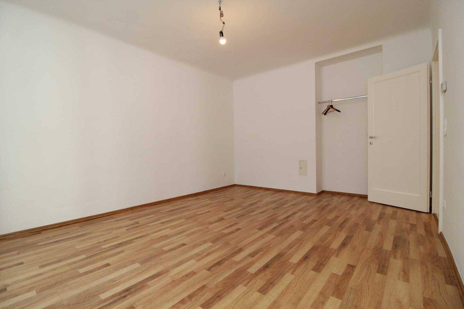 Ruhiges Schlafzimmer mit Parkettboden und praktischer Nische für einen Einbauschrank oder Kleiderschrank.
