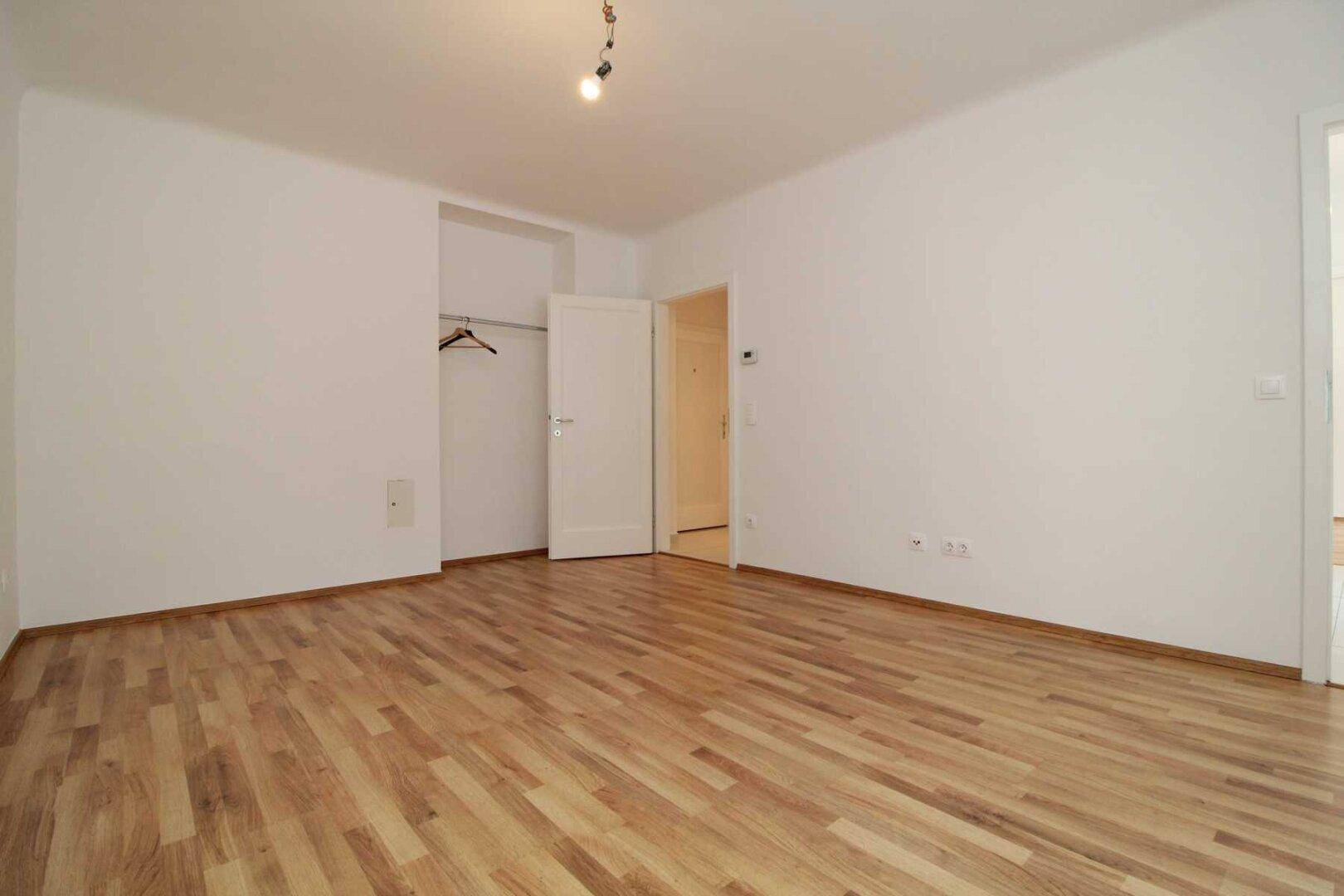 Helles Schlafzimmer mit Parkettboden und integrierter Schranknische, bietet vielseitige Einrichtungsmöglichkeiten.