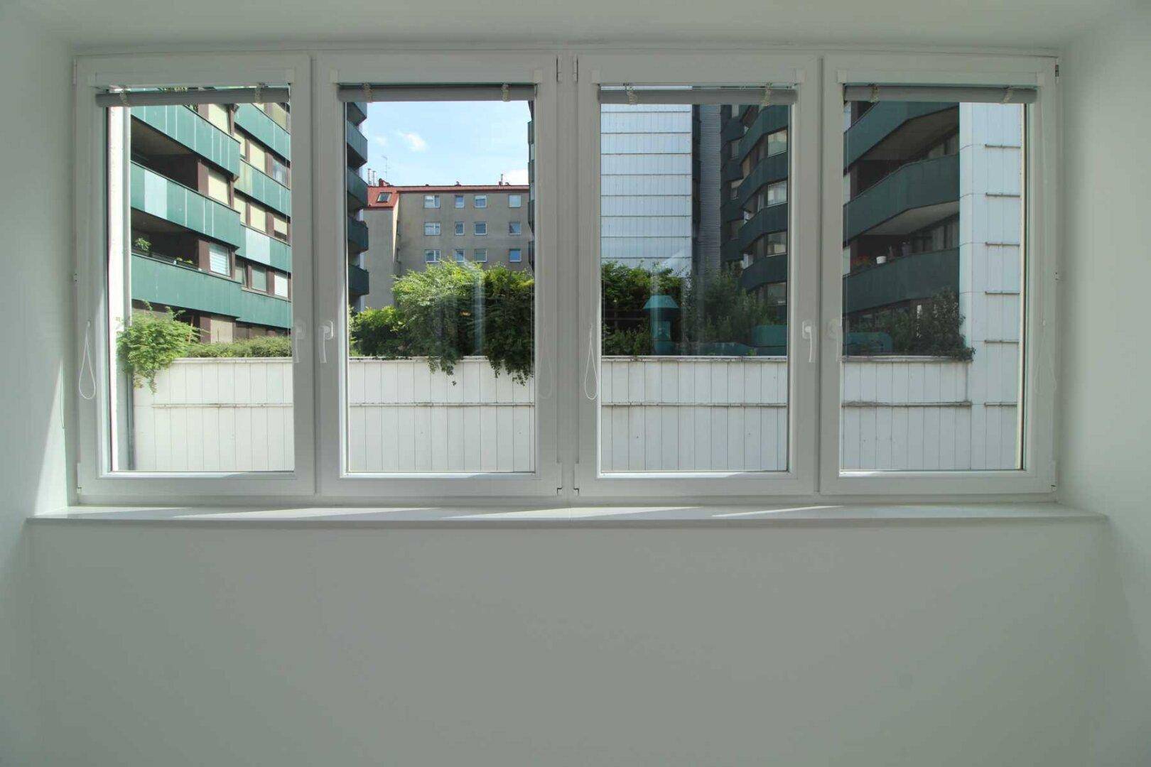 Fensterblick auf die umliegenden Gebäude und etwas Grün, bietet eine städtische Aussicht.