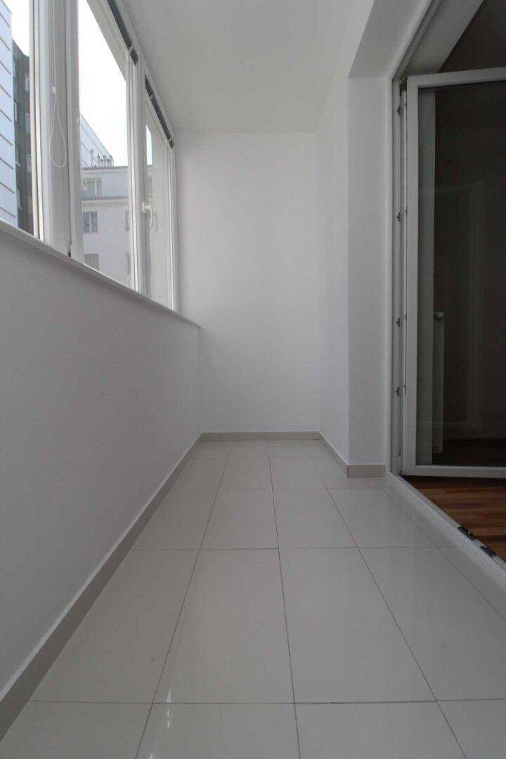 Heller Balkon mit Fliesenboden und viel Tageslicht, bietet zusätzlichen Wohnraum im Freien.