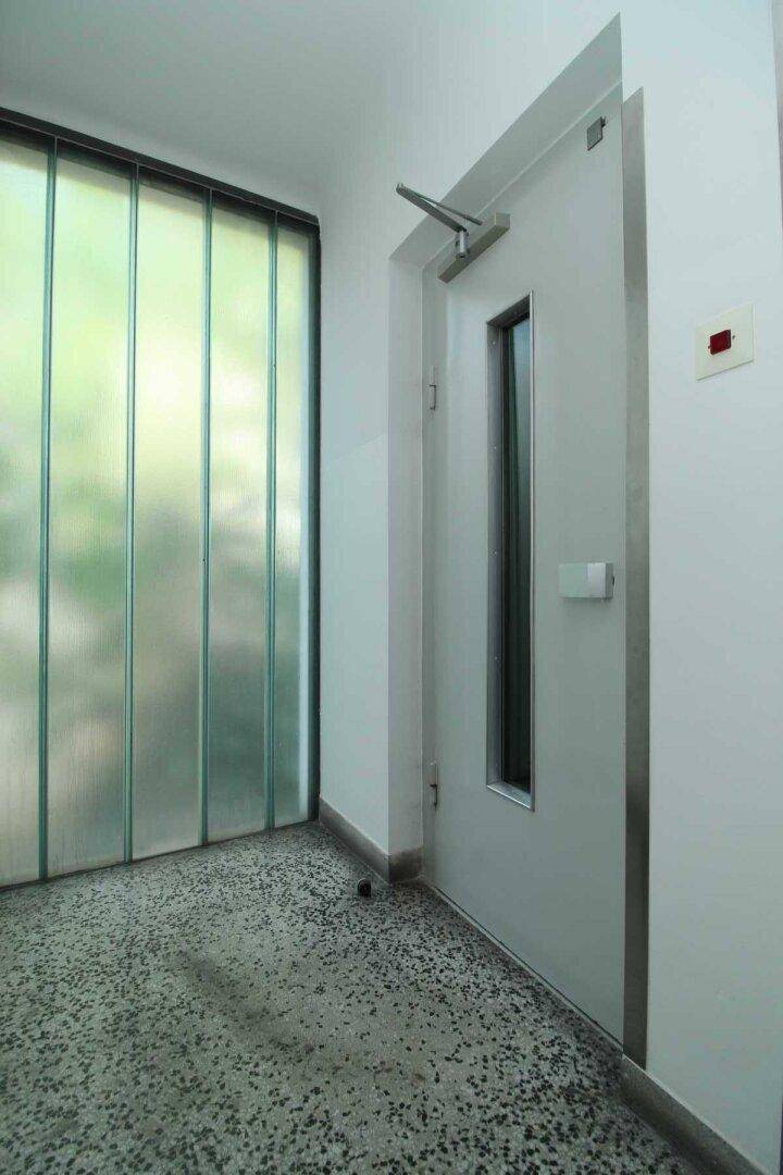 Moderner Eingangsbereich mit Glastrennwand und robuster Tür, bietet einen sicheren Zugang.