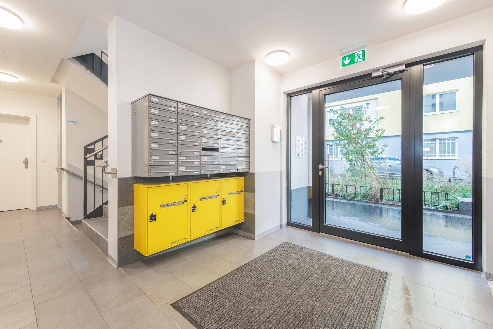 Heller Eingangsbereich des Gebäudes mit Briefkästen und Zugang zum Treppenhaus.