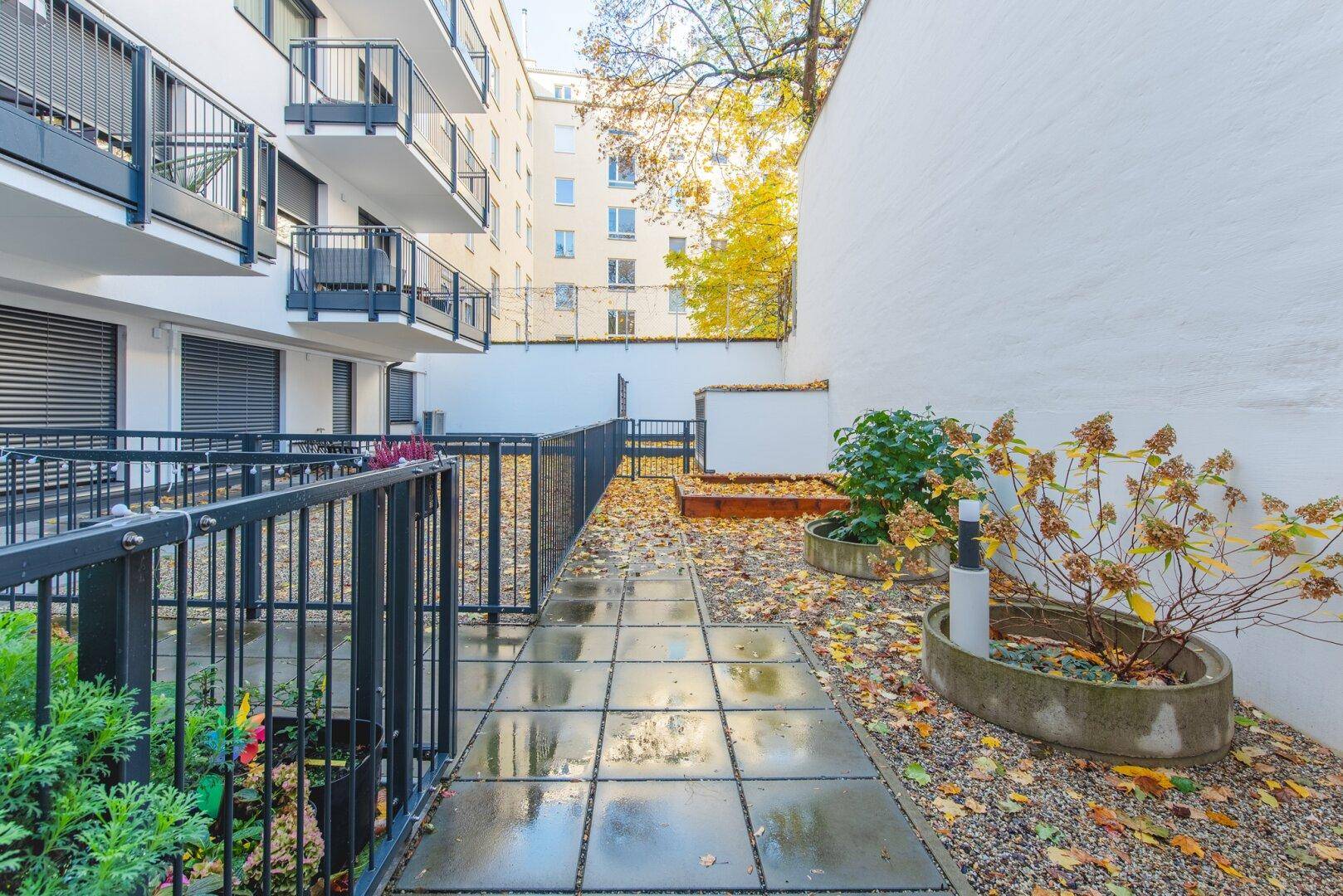 Kleiner, gepflegter Gartenbereich mit Gehwegen und Bepflanzung im Herbst.