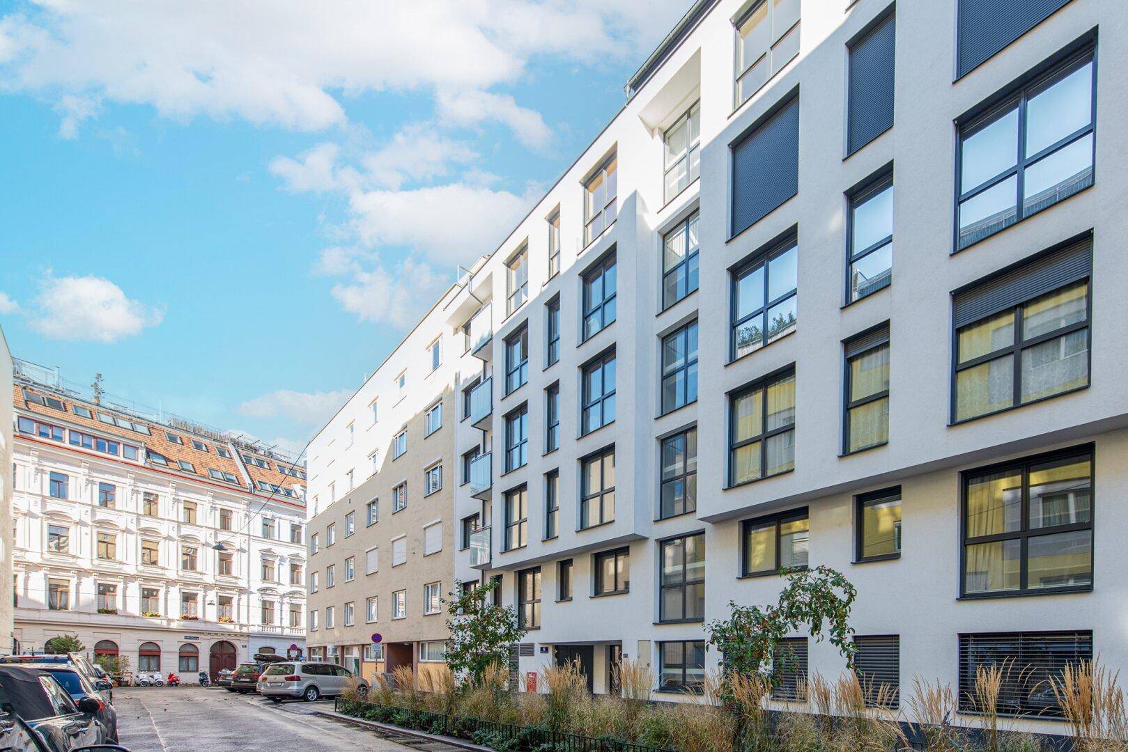 Moderne Fassade eines Neubaus in urbaner Umgebung mit großen Fenstern.
