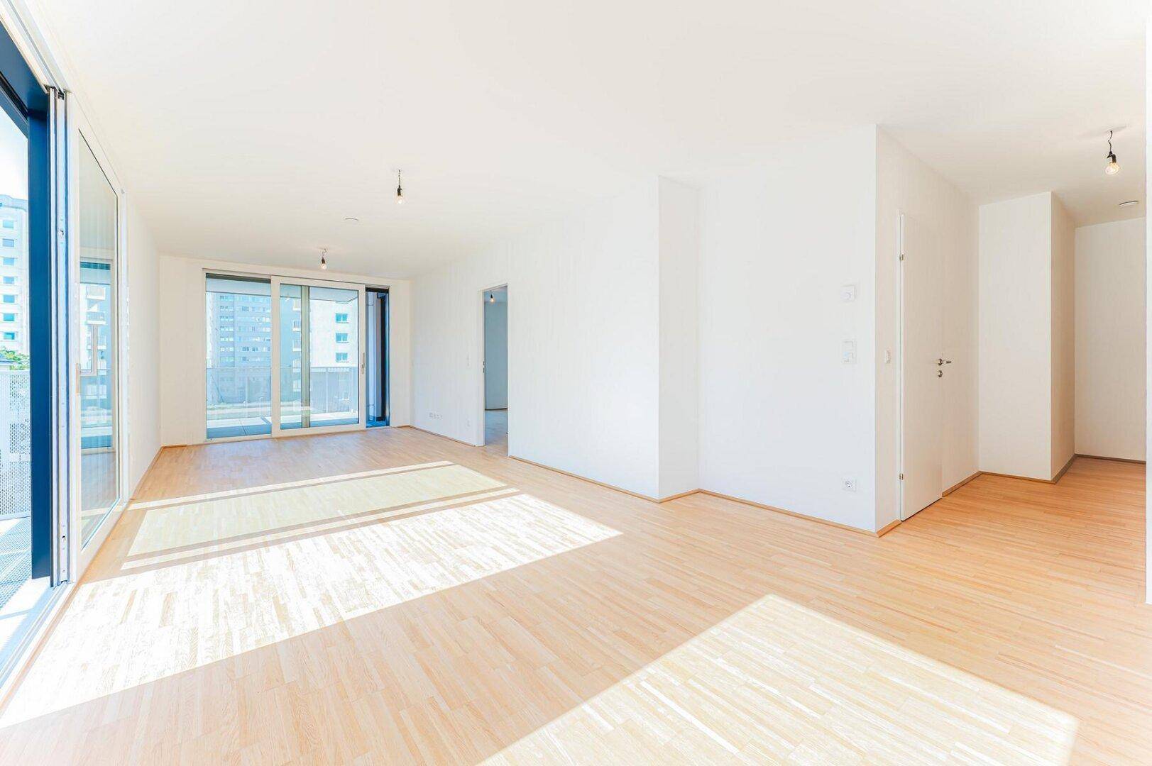 Geräumiges, helles Zimmer mit Holzboden und Zugang zu einem Balkon, ideal für einen Wohnbereich.