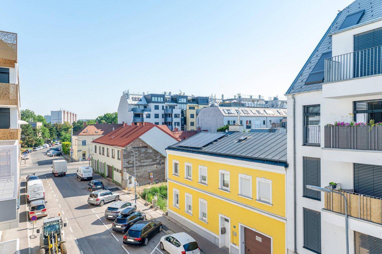 Blick von oben auf eine belebte Straße mit einer Mischung aus älteren und neueren Wohngebäuden.