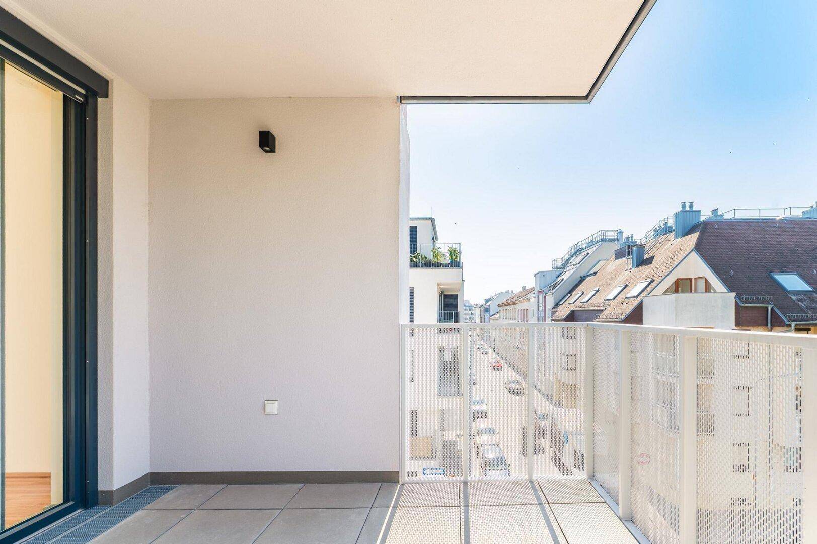 Balkon mit modernem Geländer und Fliesenboden, bietet einen klaren Blick auf die städtische Umgebung.