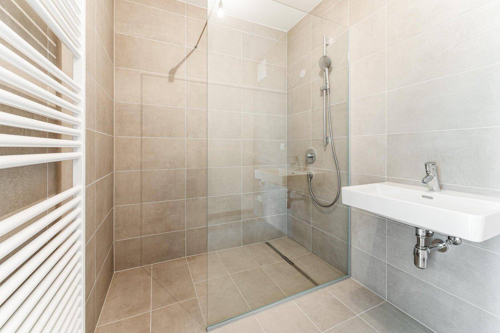 Modernes Badezimmer mit beigefarbenen Fliesen, ebenerdiger Dusche und beheiztem Handtuchhalter.