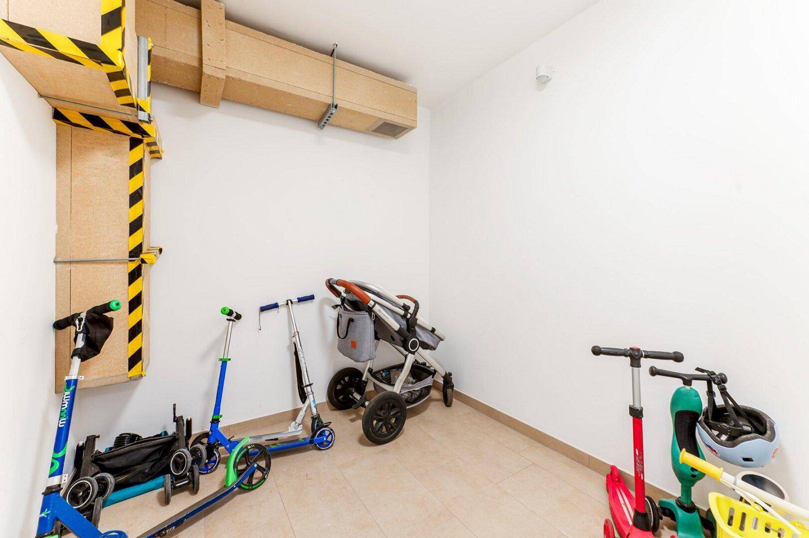 Abstellraum für Kinderwagen und Roller im Gemeinschaftsbereich, praktisch und gut organisiert.