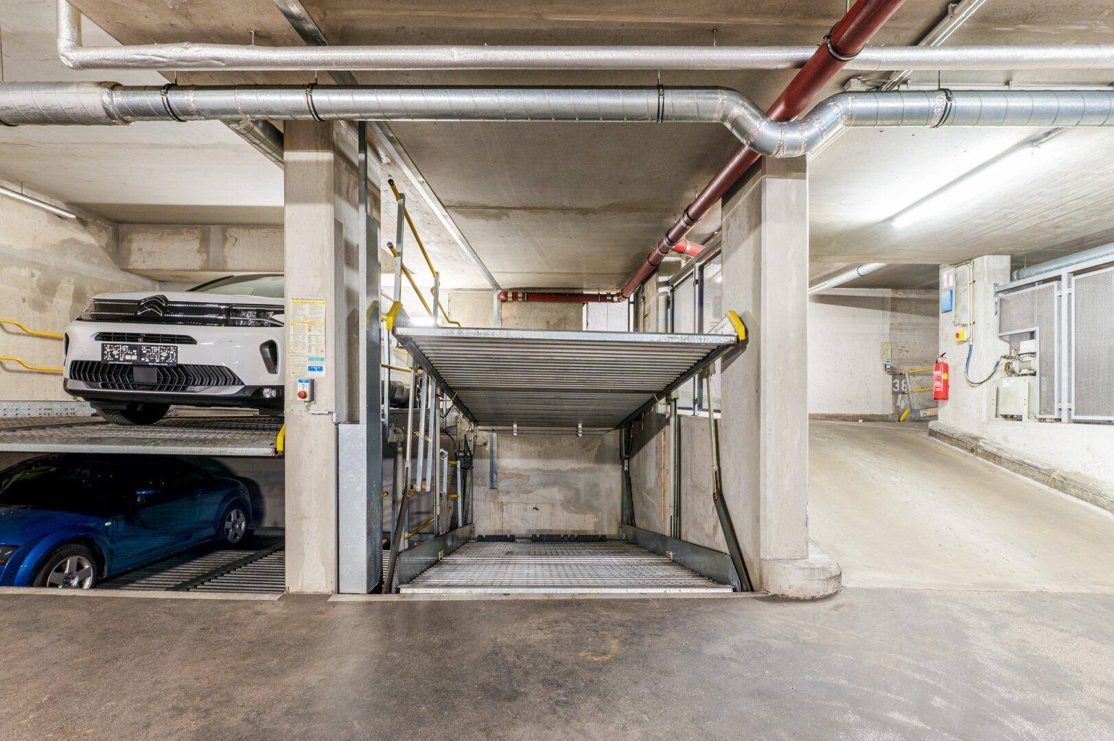 Tiefgarage mit Doppelparkern und Betonboden, bietet effiziente Parkmöglichkeiten.