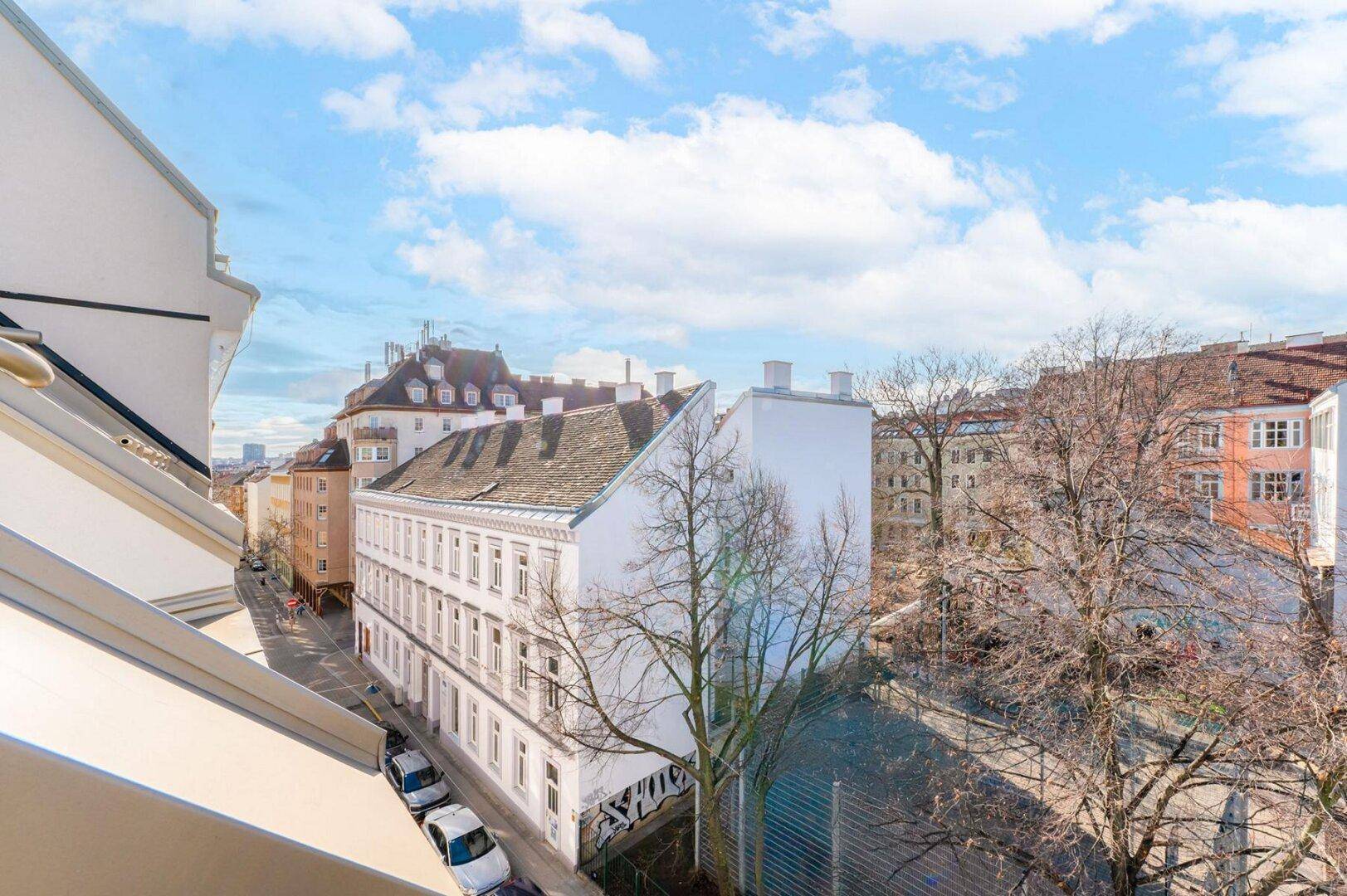 Panoramablick über die Stadt mit einer Mischung aus Alt- und Neubauten sowie einer belebten Straße.