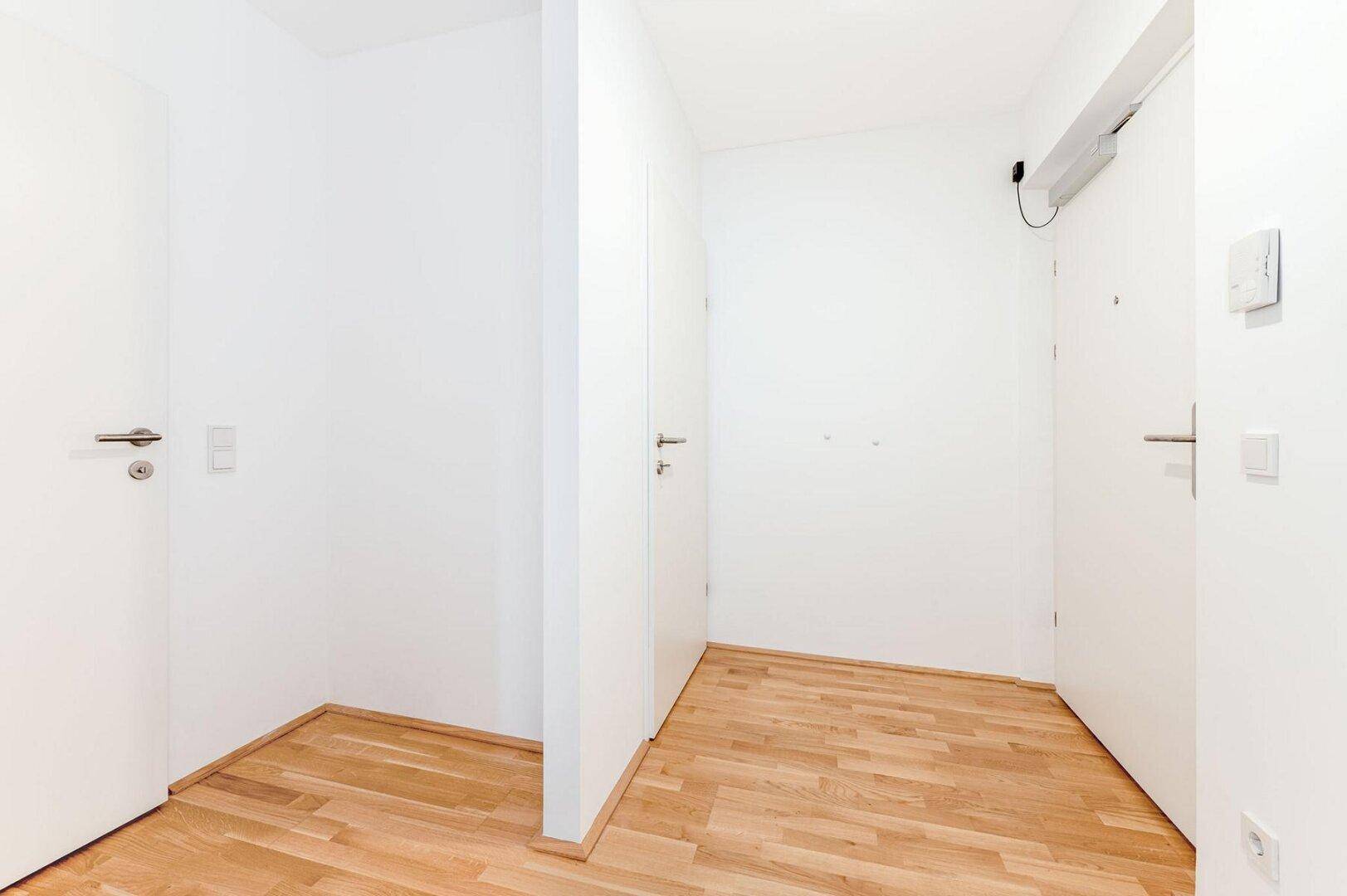 Heller Flur mit Parkettboden und mehreren weißen Türen, die zu den Zimmern führen.
