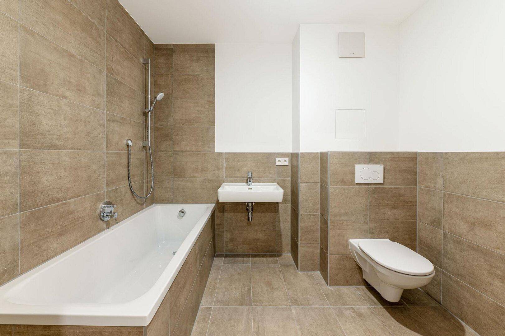Funktionales Badezimmer mit Badewanne, wandhängendem WC und Waschbecken in neutralen Brauntönen.