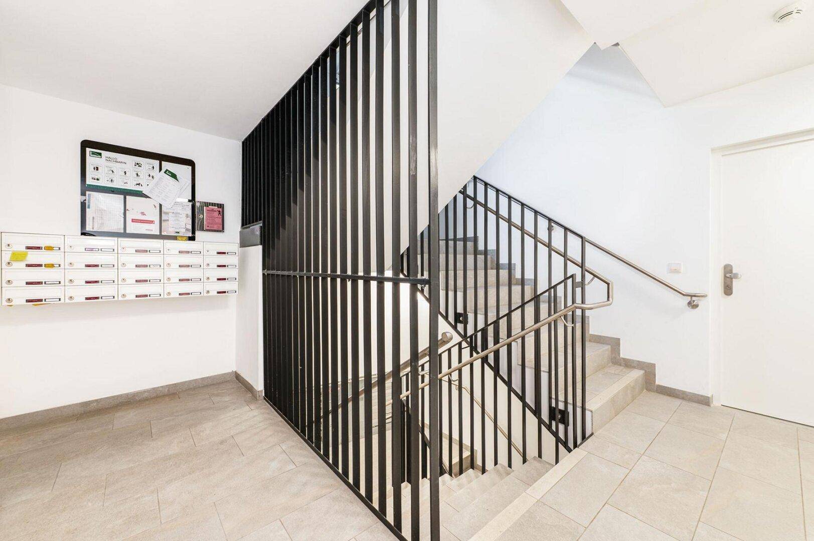 Eingangsbereich mit Treppenhaus, Briefkästen und modernem Design im Gemeinschaftsbereich.