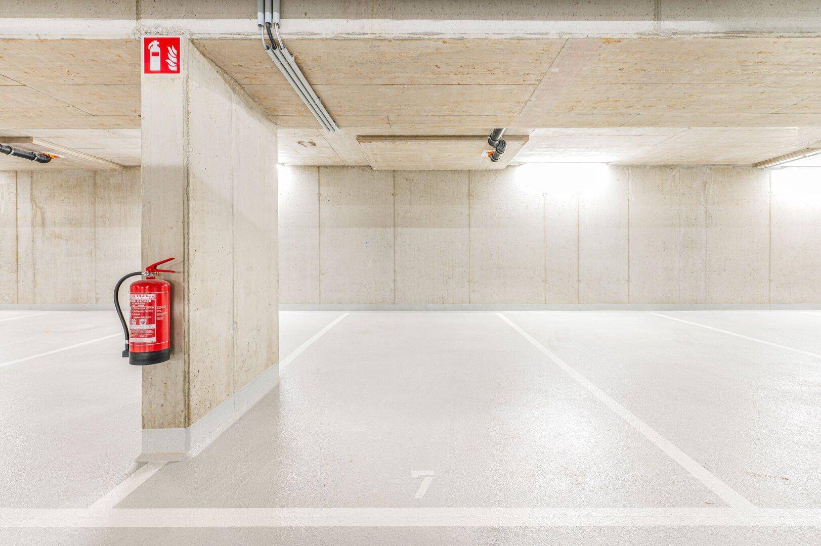 Detailansicht eines Betonpfeilers mit montiertem Feuerlöscher in der Tiefgarage.
