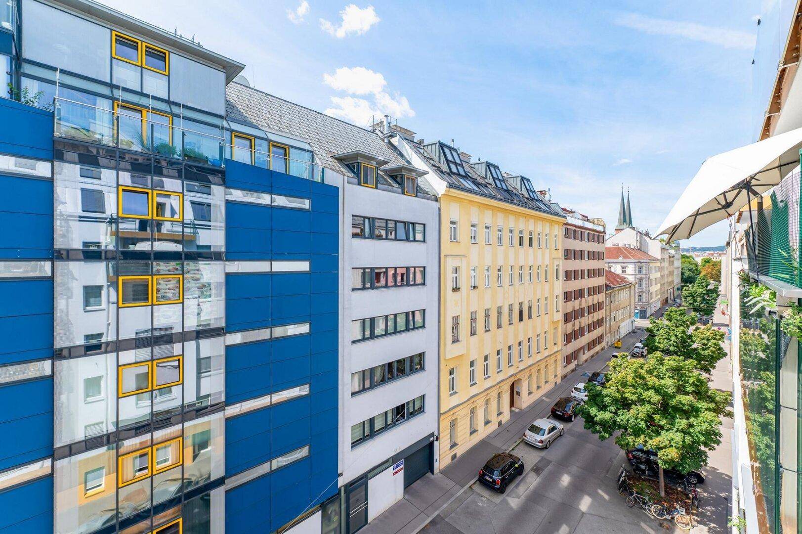 Weitblick vom Balkon auf die Stadtstraße und die umliegenden Gebäude mit moderner Architektur.