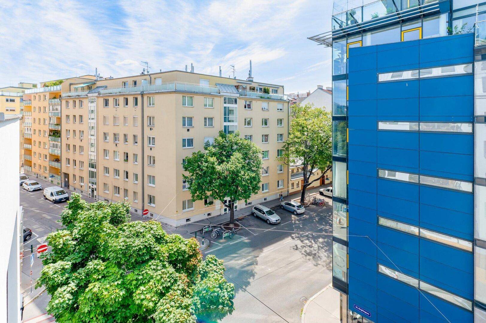 Panoramablick vom Balkon auf die Stadtlandschaft mit Bäumen und Wohngebäuden.