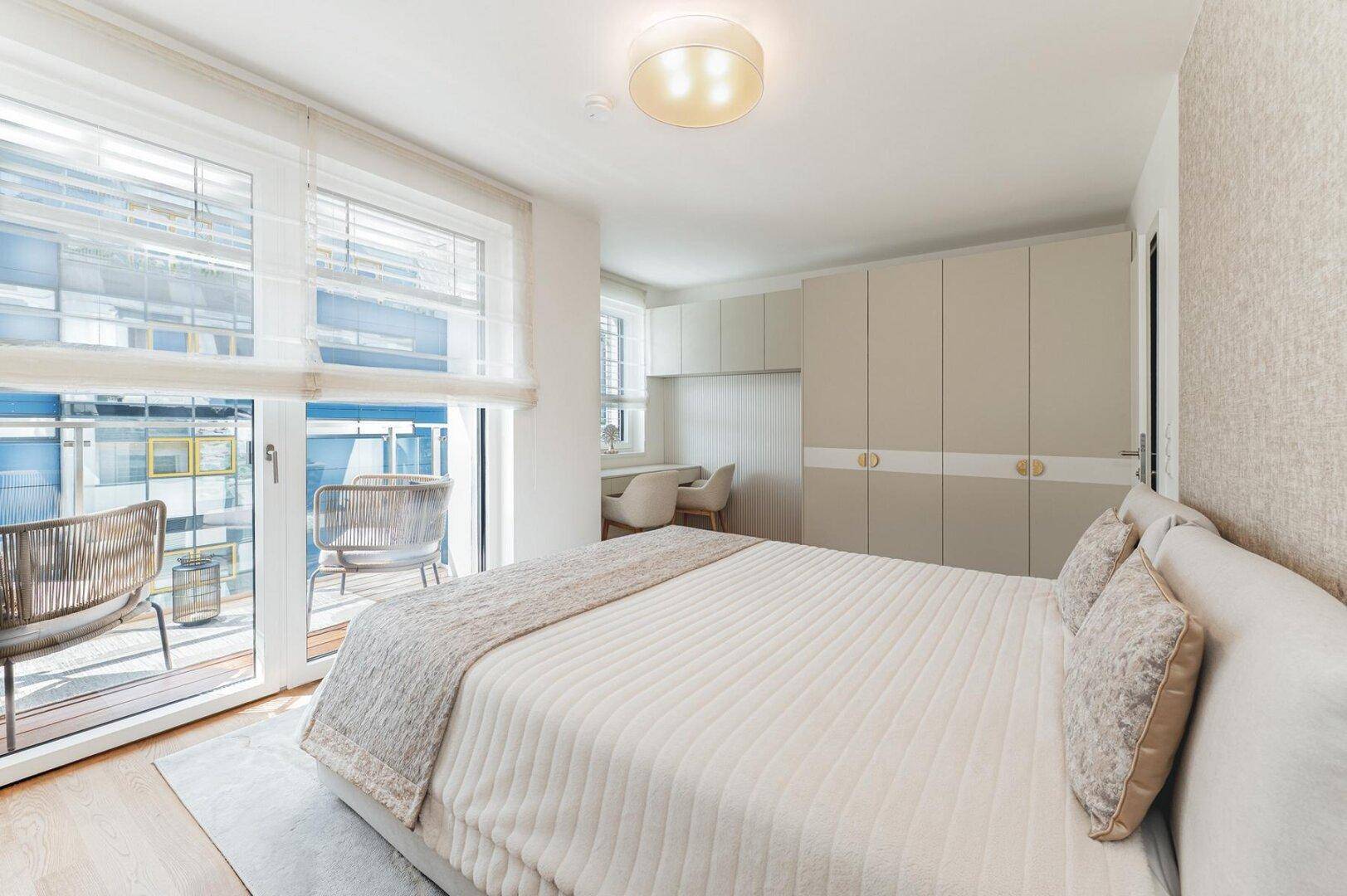 Schlafzimmer mit Doppelbett, Einbauschränken und Blick auf den Balkon durch große Fenster.