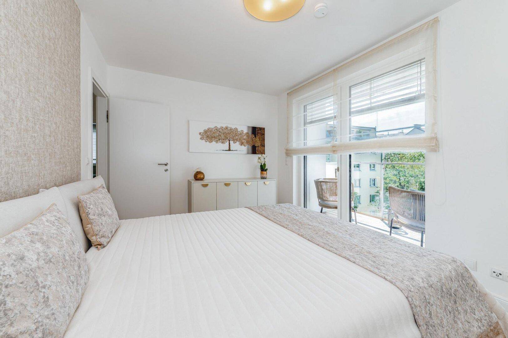 Gemütliches Schlafzimmer mit hellem Holzboden und direktem Zugang zum Balkon.