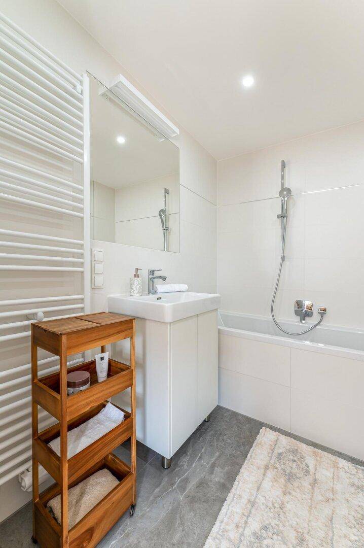 Modernes Badezimmer mit Badewanne, Einzelwaschbecken und beheiztem Handtuchhalter.