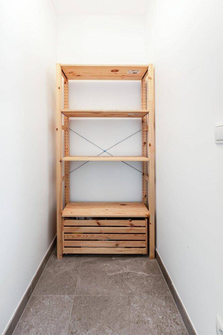 Kleiner Abstellraum mit einfachem Holzregal und Fliesenboden.