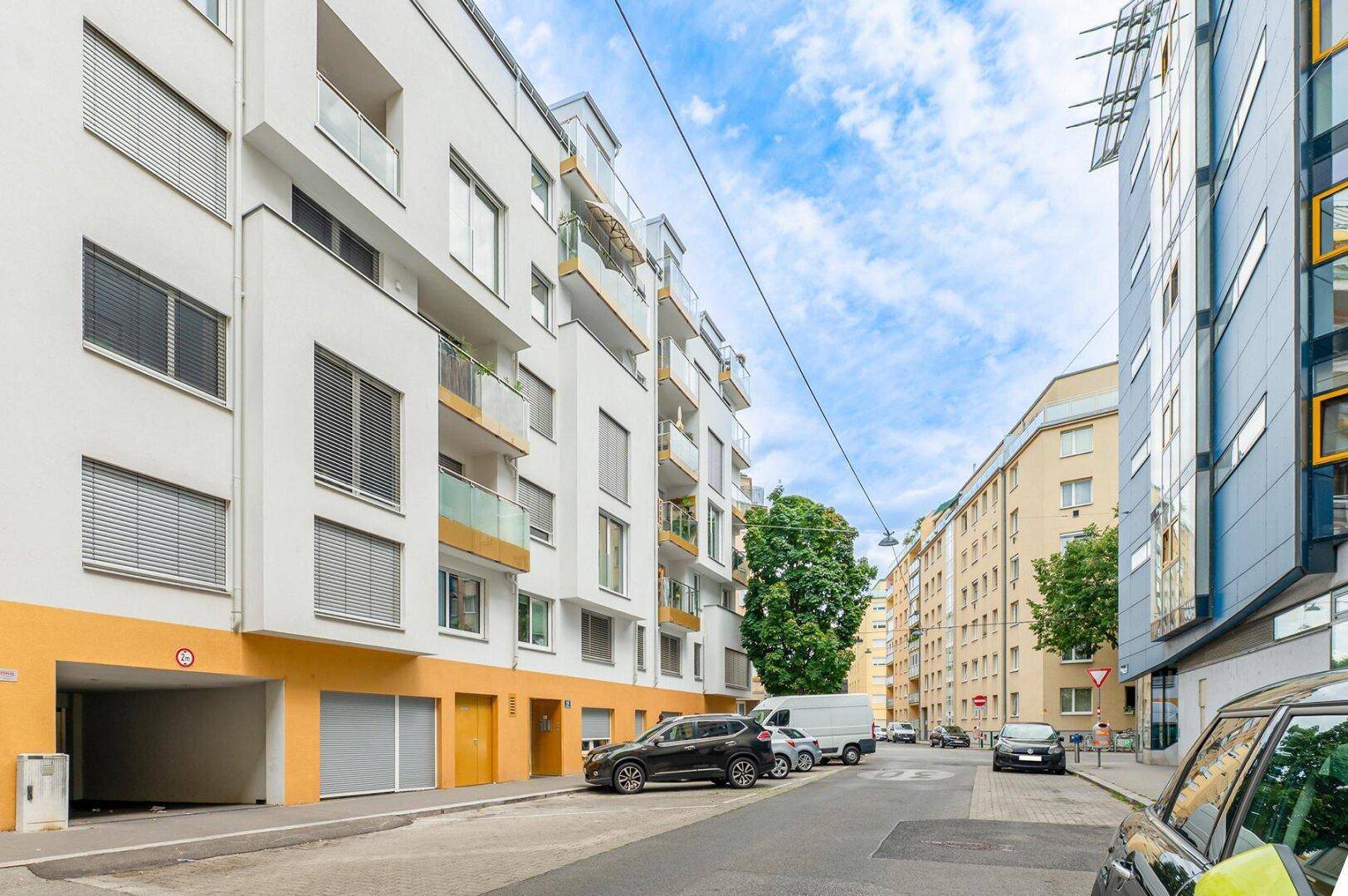 Fassade eines modernen Wohngebäudes mit Balkonen und Tiefgaragenzufahrt.