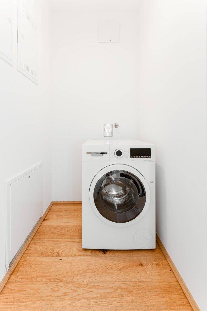 Praktischer Hauswirtschaftsraum mit Waschmaschine und Holzboden, ideal für Wäschepflege.